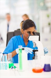 Female scientist looking through a microscope at the laboratory.