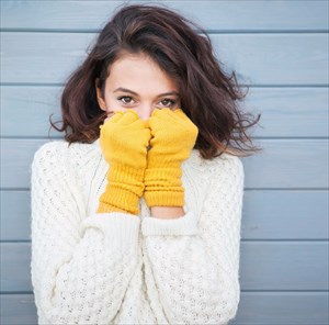 Brunette woman keeping warm with knitted sweater (jersey) and gloves.