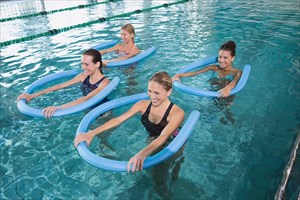 Aqua aerobics class with foam rollers in a swimming pool.