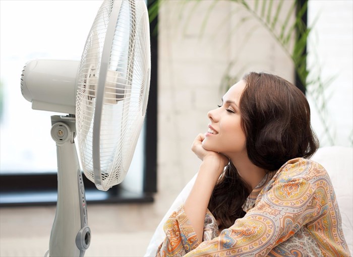 Woman sitting near a fan and cooling down.