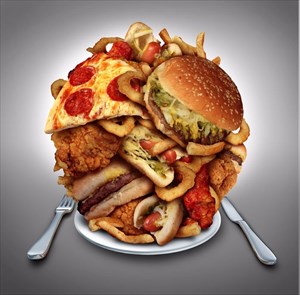 Onion rings, burger and hot dogs with fried chicken french fries and pizza on a plate (overeating concept).