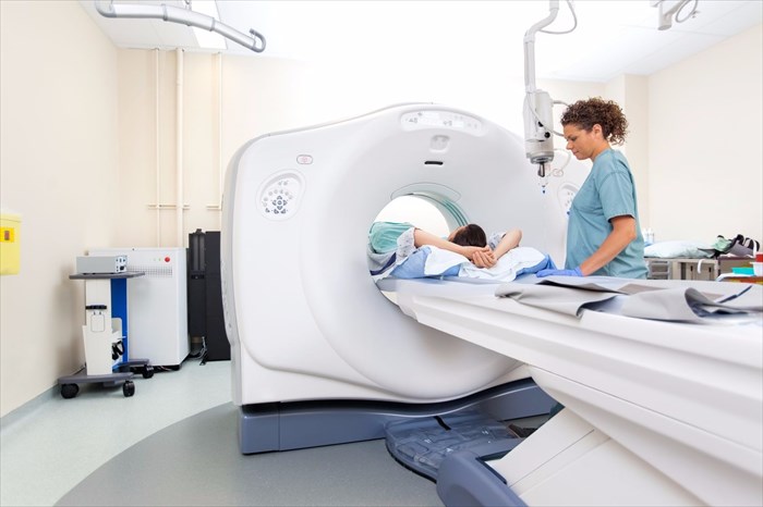 Nurse preparing a patient for a CT scan test in a hospital room.