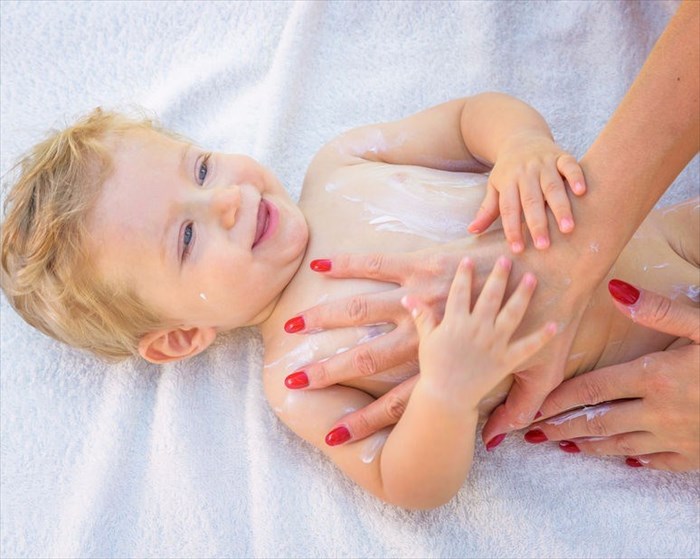 Mother applying emollient to baby