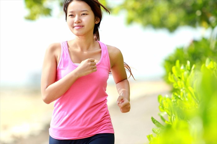 Close-up portrait of a woman in pink walking briskly on the beach.