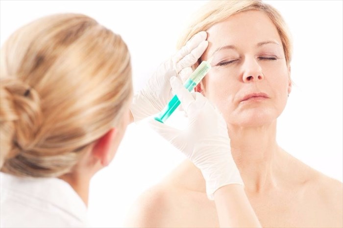 Middle-aged lady receiving filler injection to reduce lines and wrinkled in the face.