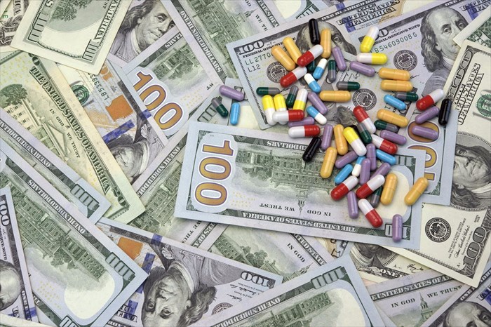 Close-up of medication atop a pile of money.