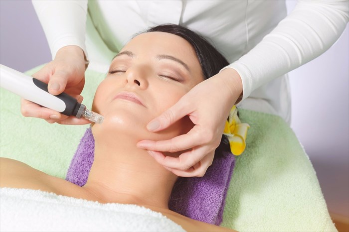 Woman having micro-needling (vampire facial) facial treatment at a beauty salon.
