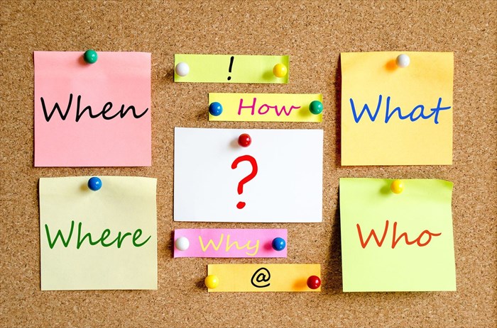 Colourful sticky note questions on a cork board background.