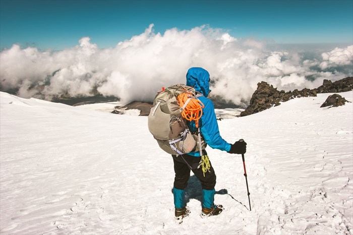 Man alpinist climbing with a backpack in the mountains.