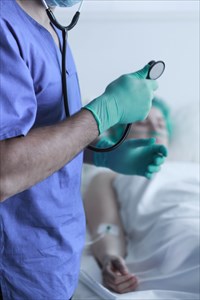 Close-up of a doctor with a stethoscope and a patient in the background.