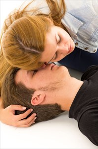 Close-up of female helper placing her ear over an unconscious patient's mouth.
