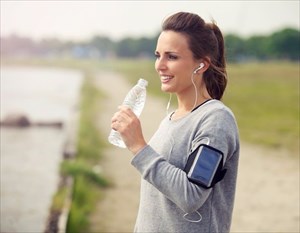 Young woman drinking a bottle of water during a run.