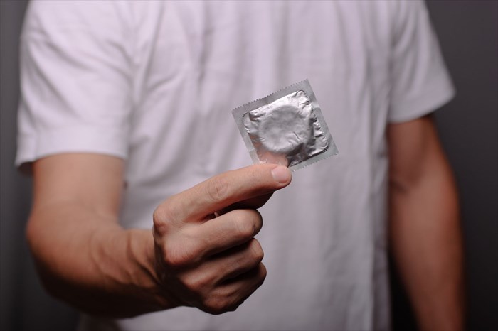 mężczyzna trzymający prezerwatywę