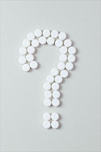 White pills question mark on grey background