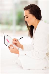 Young woman with pregnancy test writing on calendar planning her pregnancy