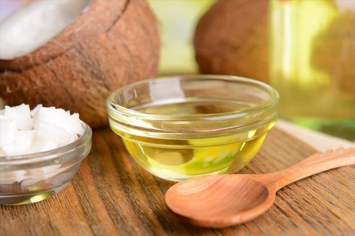 Close-up of a bowl of coconut oil and wooden spoon on a table.