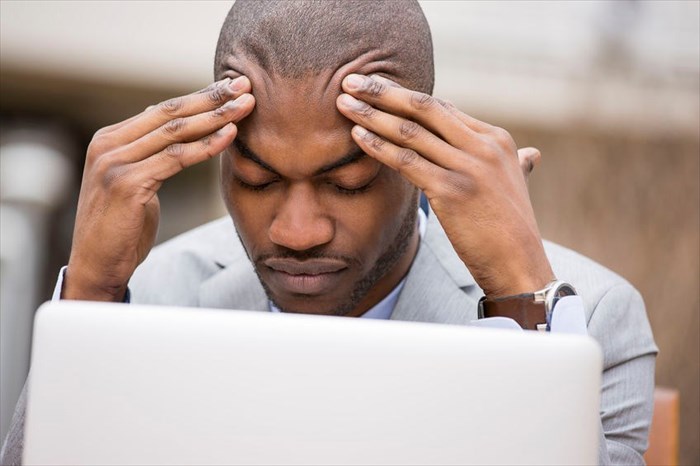 Close-up of a young man experiencing a headache.