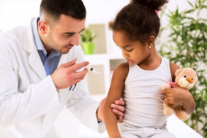 Little girl receiving a vaccination in the arm from a medical doctor.