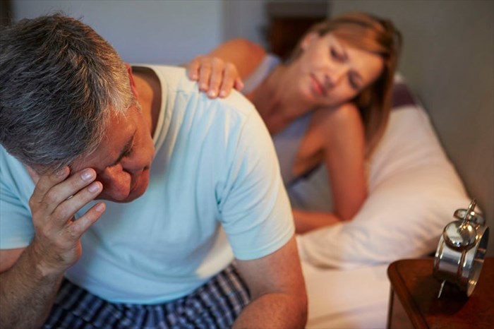 Man suffering from insomnia and being comforted by his wife 