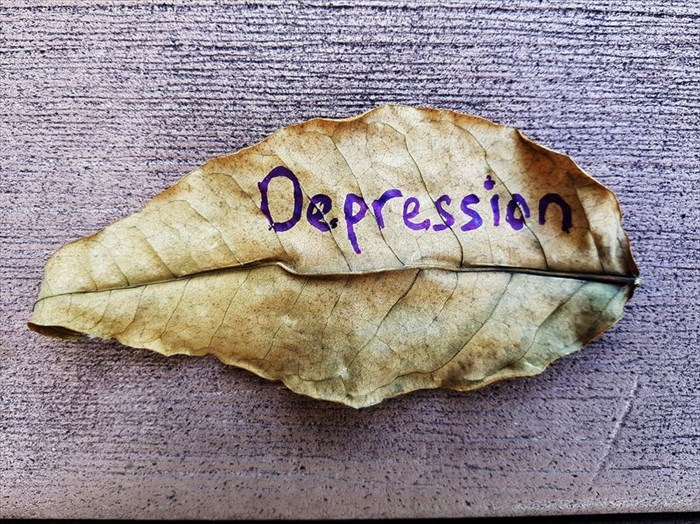 Close-up of a dried leaf with the word 'depression' written on it.