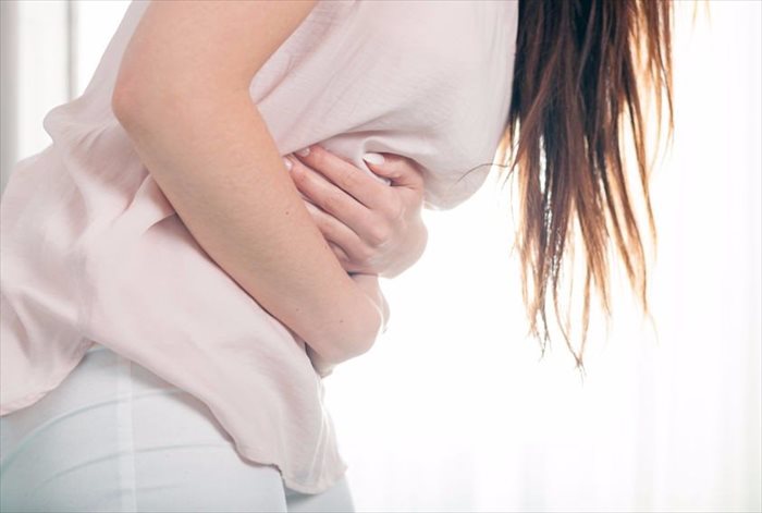 Young woman in pain holding her stomach