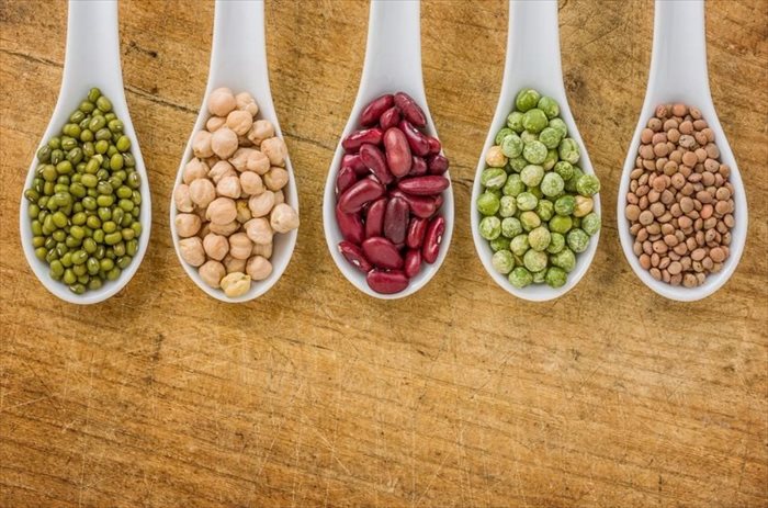 Various legumes on porcelain spoons (beans, legumes, lentils)