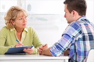 Doctor talking to her male patient (therapy / counselling)