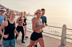 Happy men and women runners training outdoors by the seaside