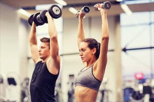 Man and woman with dumbbells flexing muscles in the gym