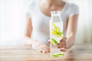 Woman with fruit and water in a glass bottle