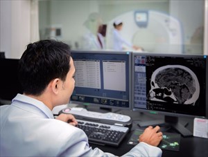 Medical team operating computers in CT scan lab for head section