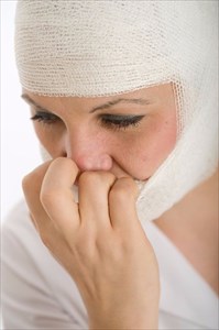 Close-up portrait of a woman with a bandaged head and face.