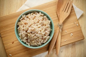 Brown rice in a bowl on a wooden board.