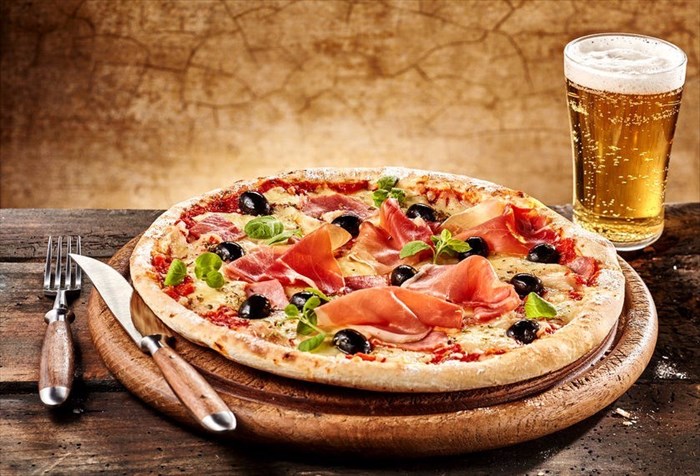 Serving of bacon pizza and a glass of beer.